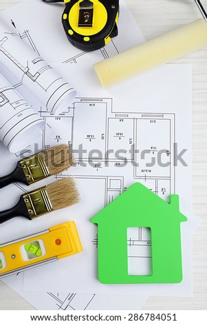 Construction instruments, plan and brushes on wooden table background