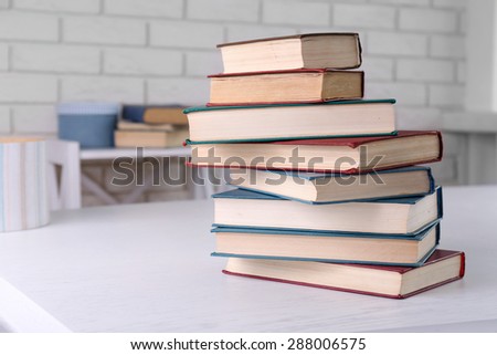 Stack of books on light surface, om bricks wall background