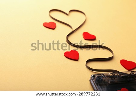Audio cassette with magnetic tape in shape of heart on yellow background