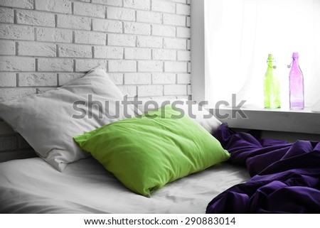 Comfortable bed with green pillow and purple blanket  in bedroom