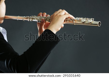 Musician playing flute on dark background