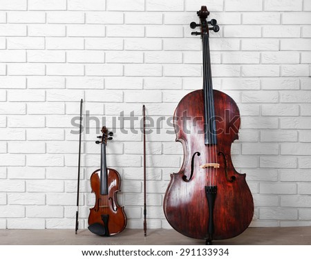 Cello and violin on bricks wall background