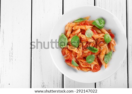 Pasta with tomato sauce and basil on wooden table close up