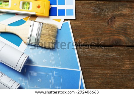 Construction instruments, plan and brushes on wooden table background