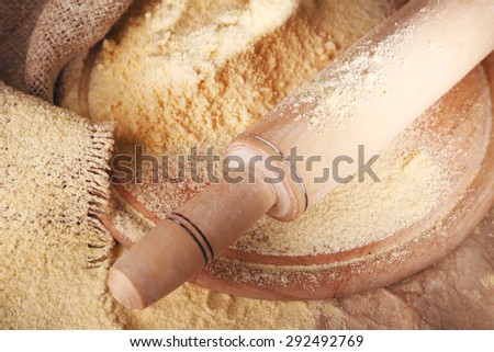 Whole flour with rolling pin on wooden cutting board, closeup