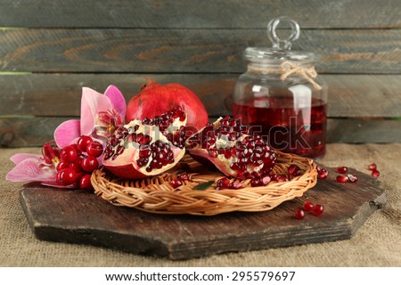 Pomegranate seeds on wicker tray and jar of juice on wooden background