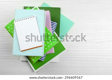 Notebook on top of pile of books and magazines on wooden background