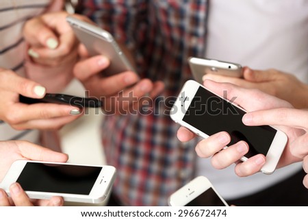Many hands holding mobile phones close up