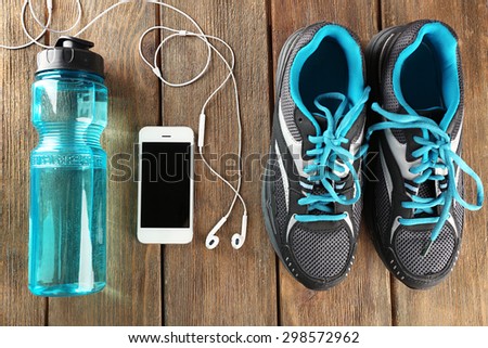 Sneakers and earphones on wooden table, top view