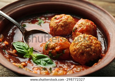 Meat balls with tomato sauce and wooden spoon, close-up