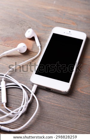 Mobile phone and earphones on wooden background