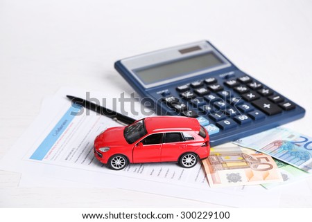 Toy car, money, documents and calculator on table. Car insurance concept