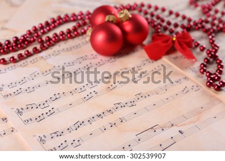 Christmas ball, beads and bow on music sheets background