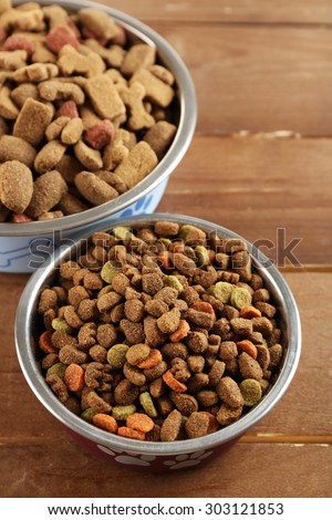 Dog food in bowls on wooden table