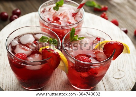 Glasses of berry juice on wooden table, closeup