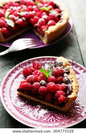 Piece of tart with fresh raspberries, on wooden background