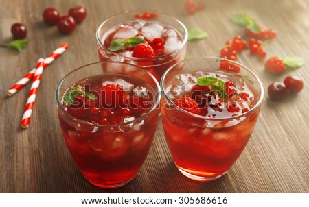 Glasses of berry juice on wooden table, closeup