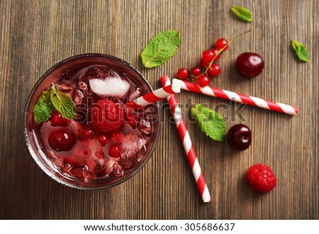Glass of berry juice on wooden table, top view