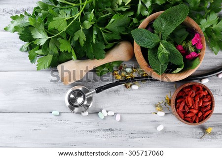 Alternative medicine herbs, berries and stethoscope on wooden table background