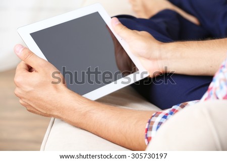 Male hand holding PC tablet on home interior background