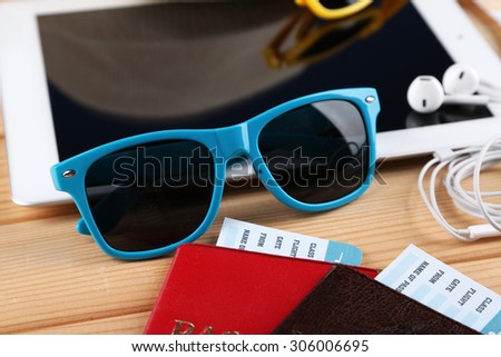 Sunglasses, passports, tickets, PC tablet, close up, on wooden background. Preparing for travel concept