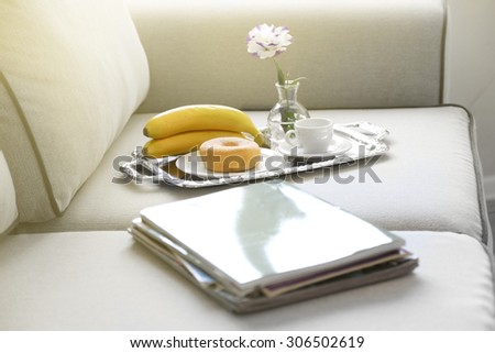 Light breakfast and magazines on sofa in living room, close up
