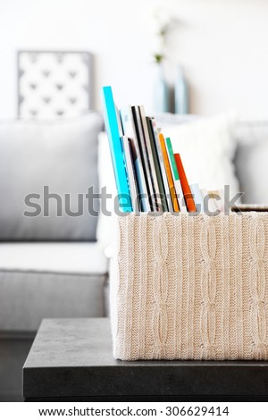 Magazines in basket on table in living room, close up