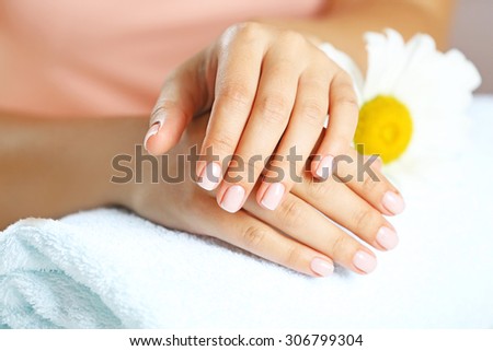 Woman hands with french manicure and chamomile on towel close-up