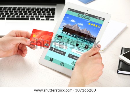 Man holding tablet with screen interface of booking hotels