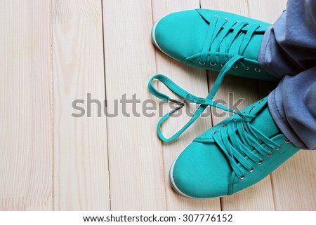 Female feet in gum shoes on wooden floor background