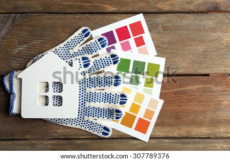 Color samples, gloves and decorative house on wooden table background