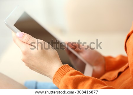 Female hand holding PC tablet on home interior background