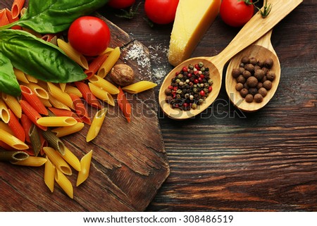 Pasta penne with tomatoes, cheese, spices and basil on rustic wooden  background