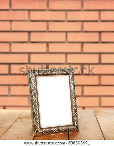Old empty frame standing on table on brick wall background