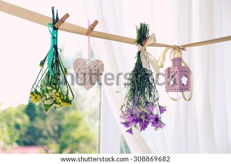 Various herbs, flowers and decorations hanging on thong on light background