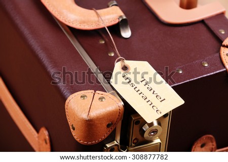 Suitcase with TRAVEL INSURANCE label, closeup