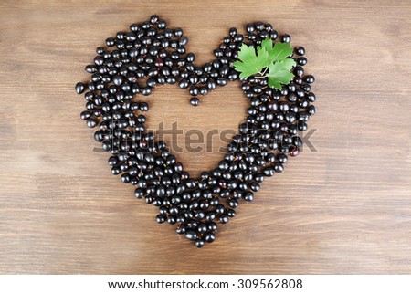 Black Currant in shape of heart on wooden background