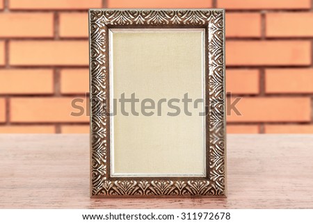Old empty frame on table on brick wall background