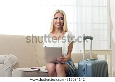 Woman with suitcase and tablet after traveling at home