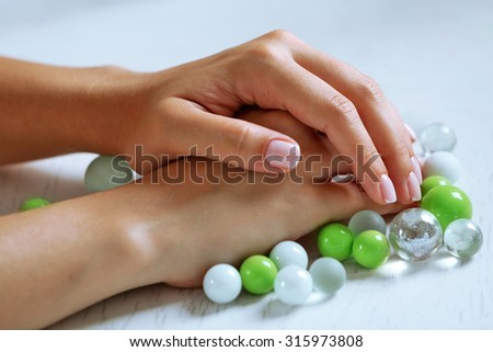 Woman hands with french manicure and glass beads on table close-up