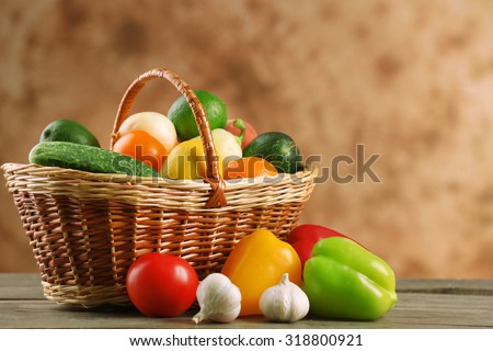 Heap of fresh fruits and vegetables in basket on wooden table close up