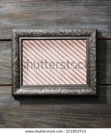 Old frame with striped canvas on wooden background