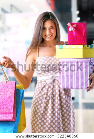Beautiful young woman with shopping bags and boxes in the mall