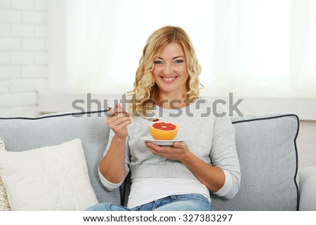Beautiful woman with grapefruit d on home interior background
