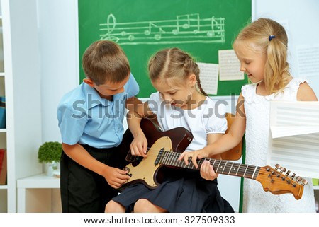 Cute pupils having music lesson in classroom at elementary school