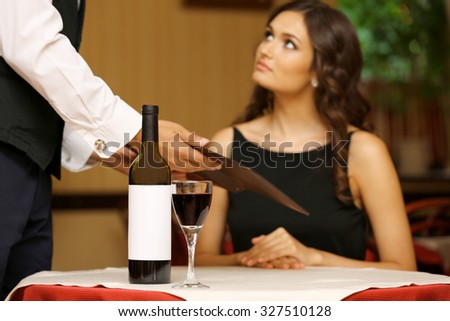 Young pretty lady at the restaurant. Waiter takes menu