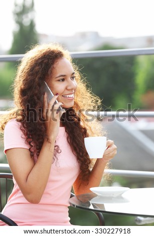 Close up portrait of pretty young woman speaking by cellphone and drinking coffee
