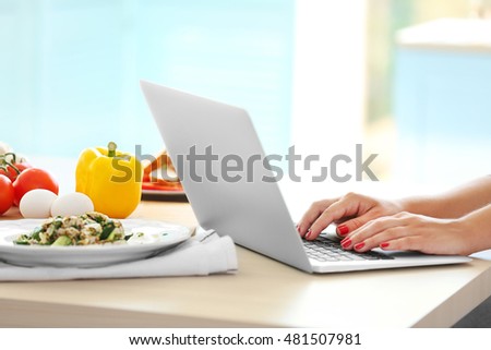 Someone using a laptop on a table filled with food items