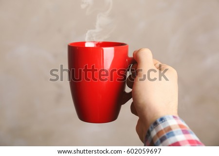 Similar – Image, Stock Photo Hand holding red cup with steaming drink against the light