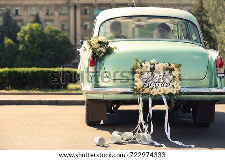 Wedding couple in car decorated with plate JUST MARRIED and cans outdoors Foto stock © 
